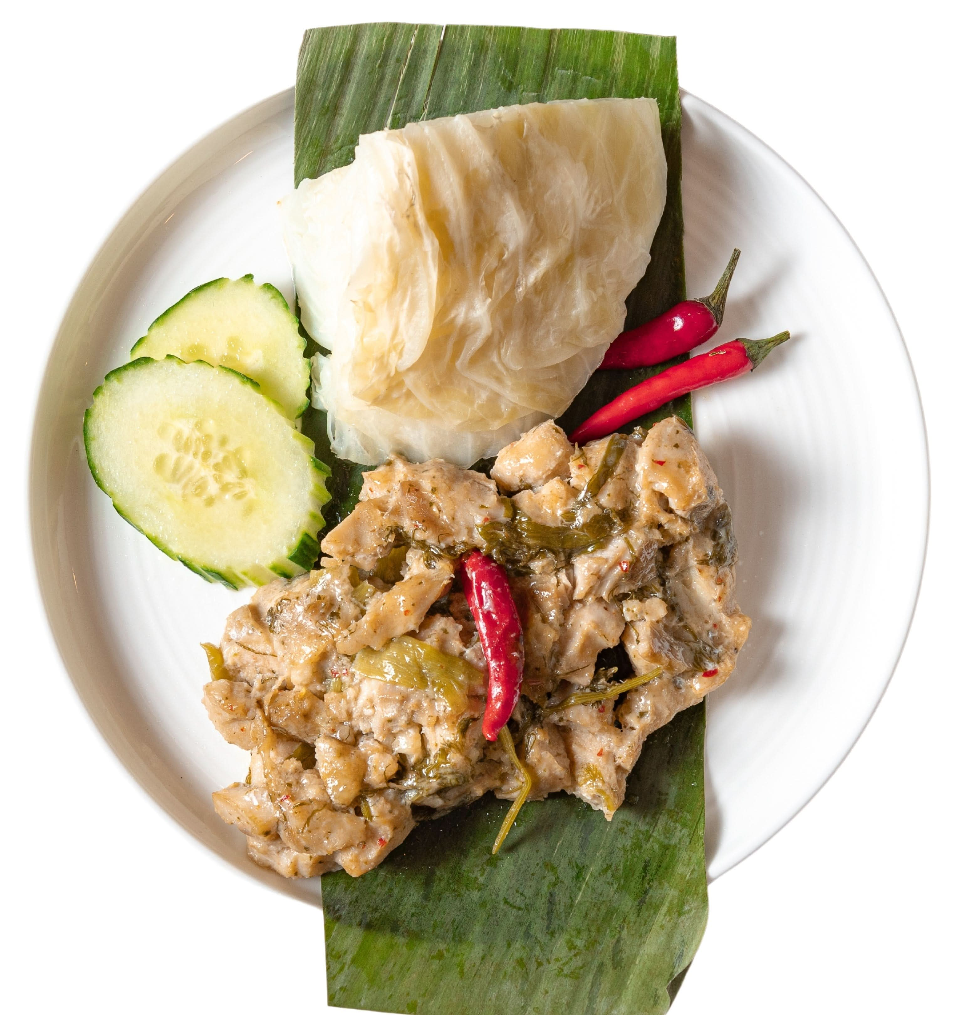 This is steamed chicken in banana leaves served on a plate.