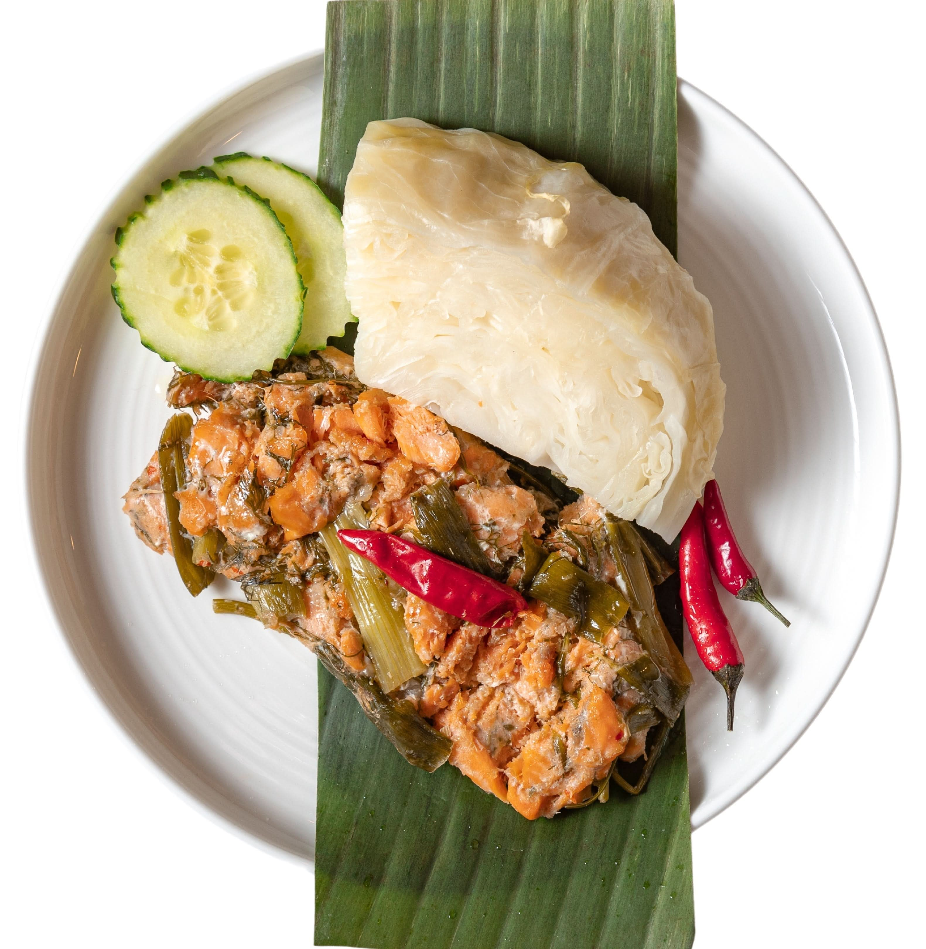 This is salmon steamed in banana leaves that is served on a plate.