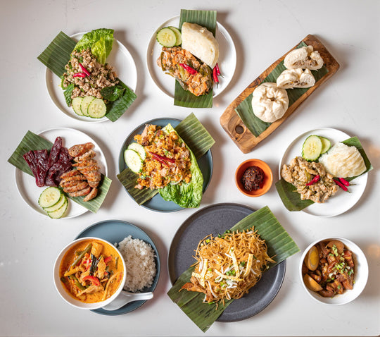 Nine Laos prepared meals and dipping sauce on plates.