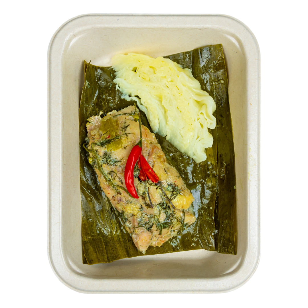 Steamed chicken in banana leaves with steamed cabbage in a compostable meal tray.