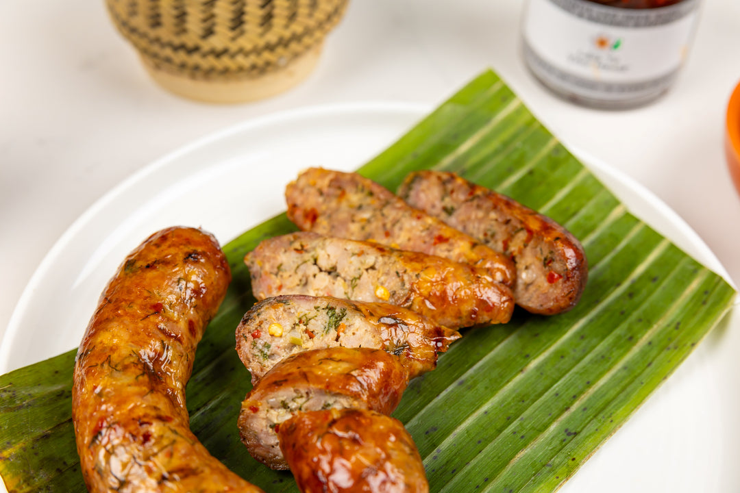 Spicy grilled sausage sliced open on a banana leaf.