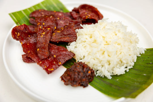 Lao Beef Jerky on a plate with jasmine rice and spicy dipping sauce.