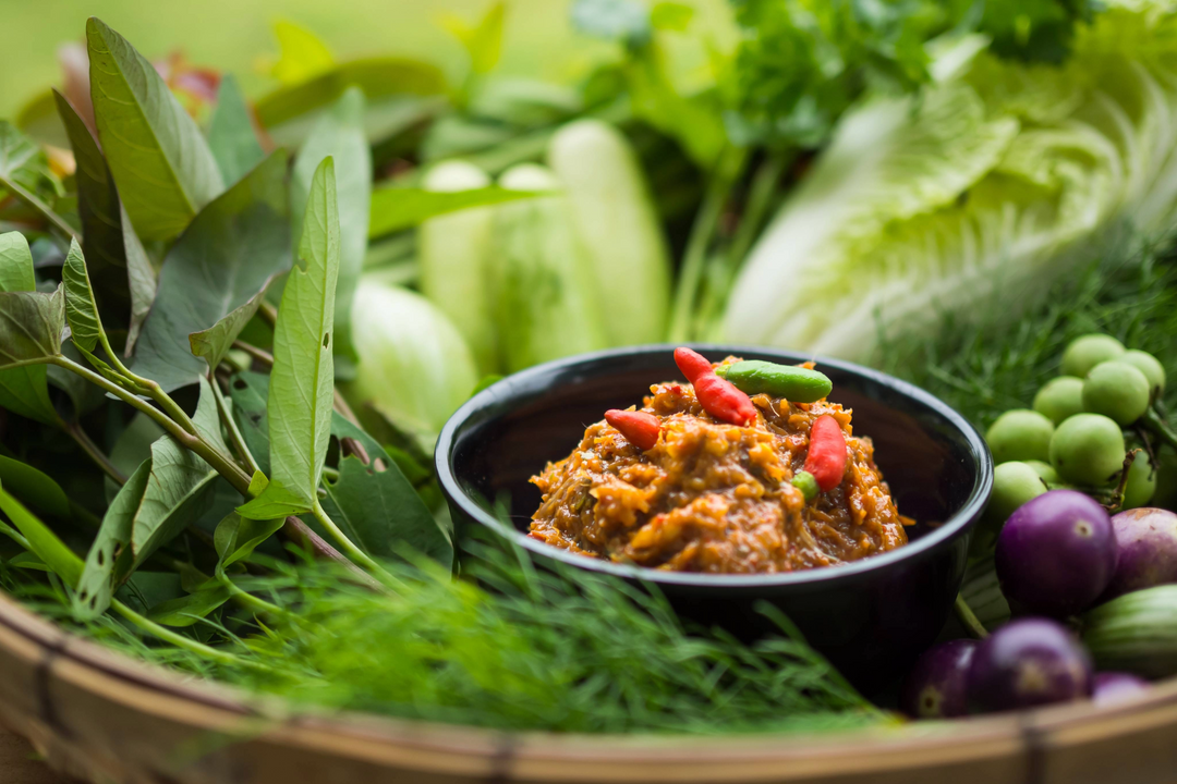 Sauce from the country of Laos surrounded by vegetables and herbs. 